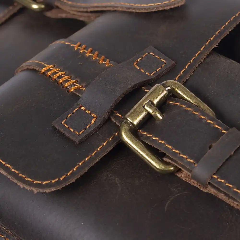 Close-up of a vintage dark brown leather bag with detailed stitching and brass buckle.