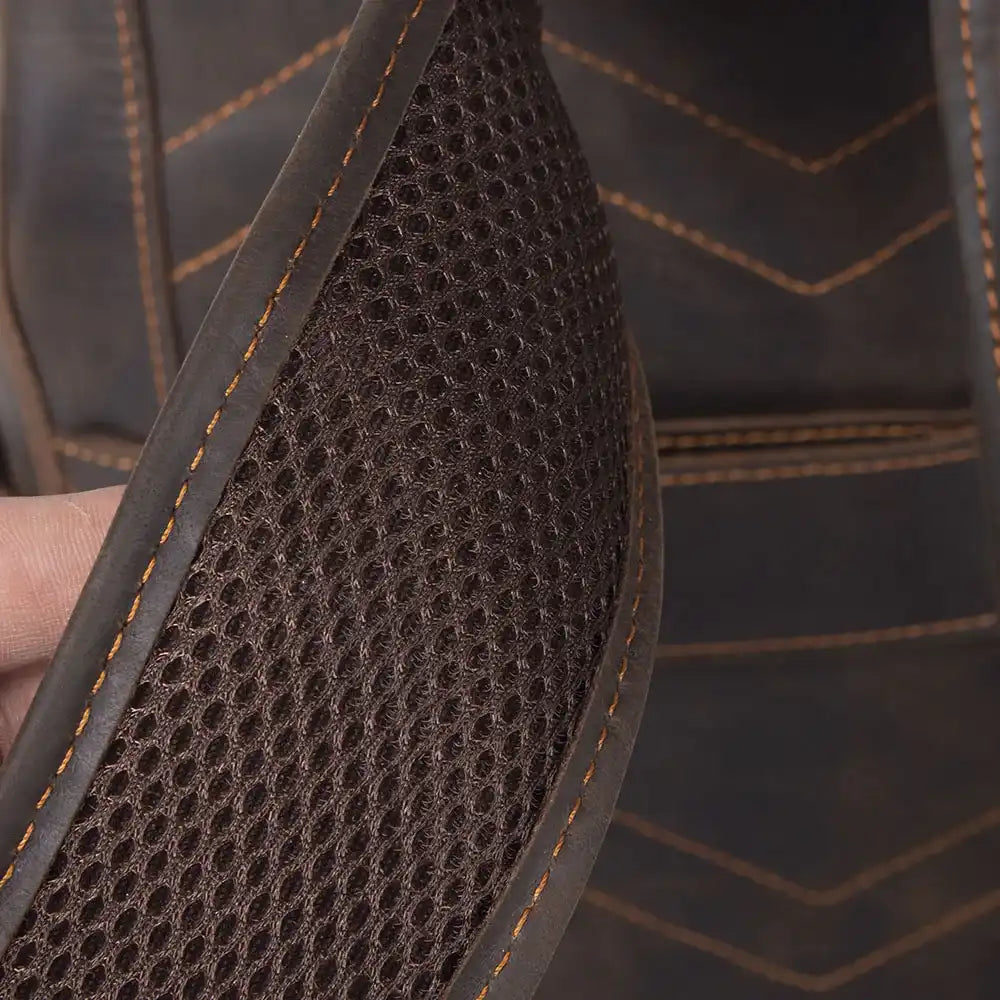  Close-up of breathable mesh material with a dark brown color and orange stitching.