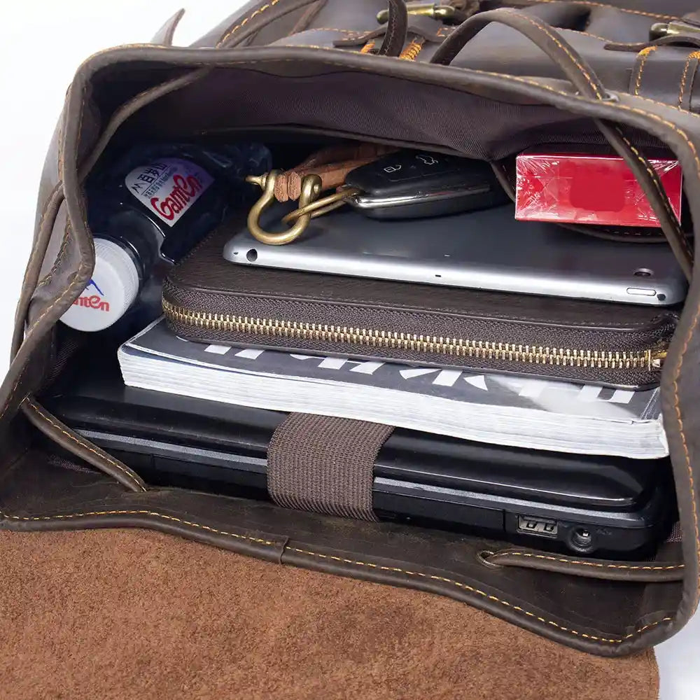 Inside view of a leather bag showing a laptop, notebook, water bottle, and keys showcasing bag capacity.