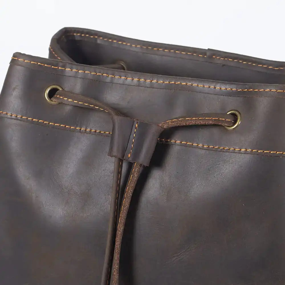 Close-up view of a brown leather drawstring bag showcasing its texture and stitching.