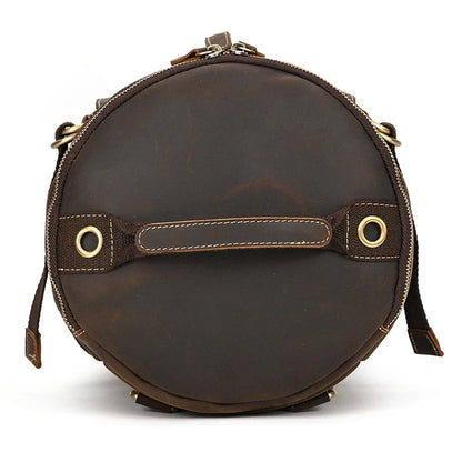 Round shaped dark brown leather duffle bag. Elegant and functional design, with handles and zipper closure, top view.