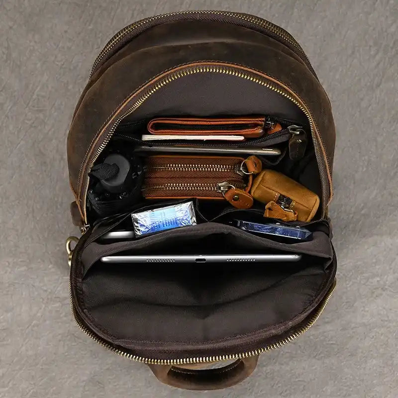 interior of a leather bag with several items organized inside, including a wallet, notebook and electronics showcasing capaciy.