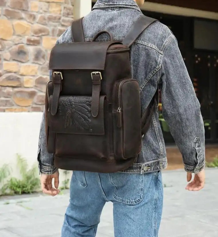 a dark leather backpack, modern style, carried by a man wearing a denim jacket.