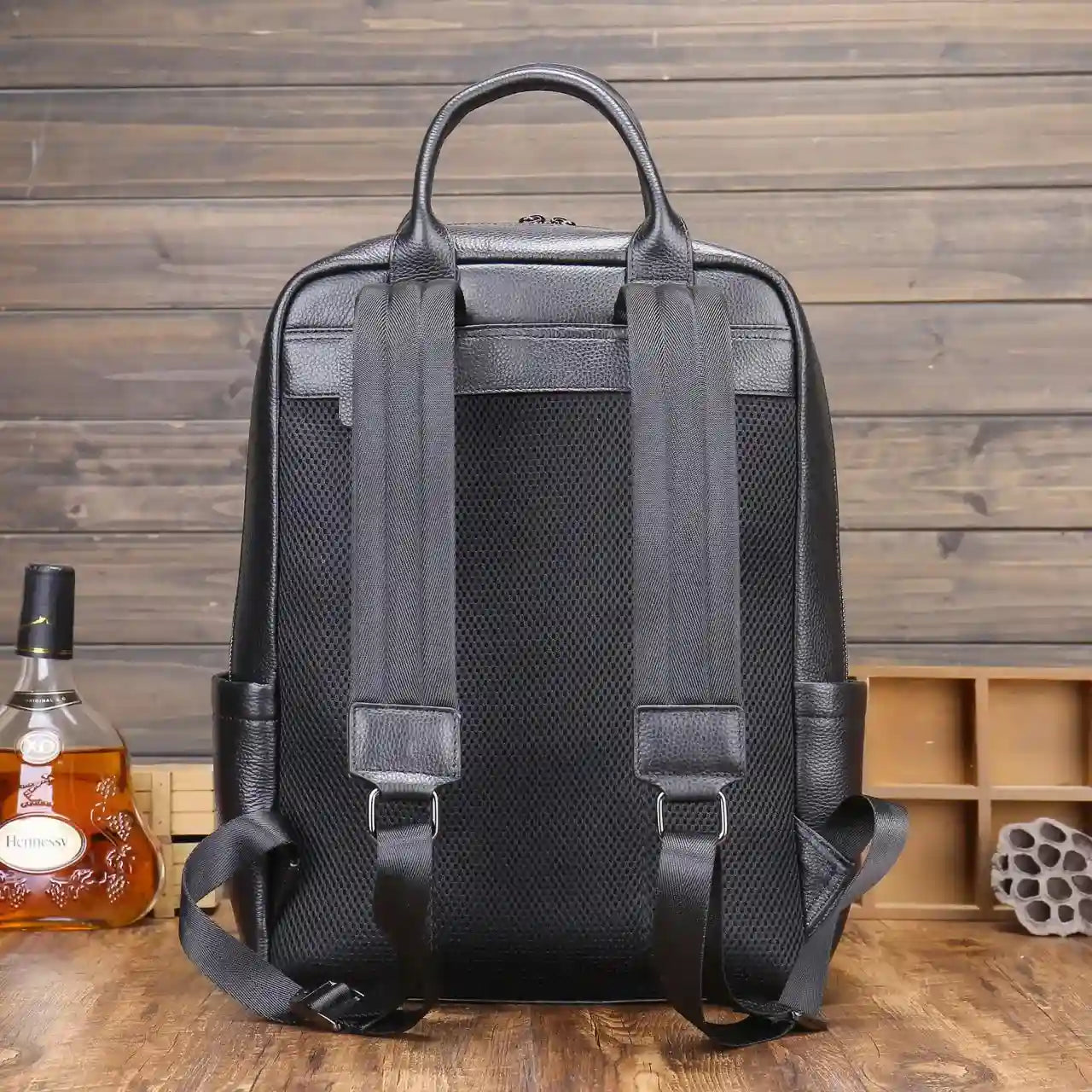 ergonomic design of a  black leather backpack with padded straps and mesh backing - back view.