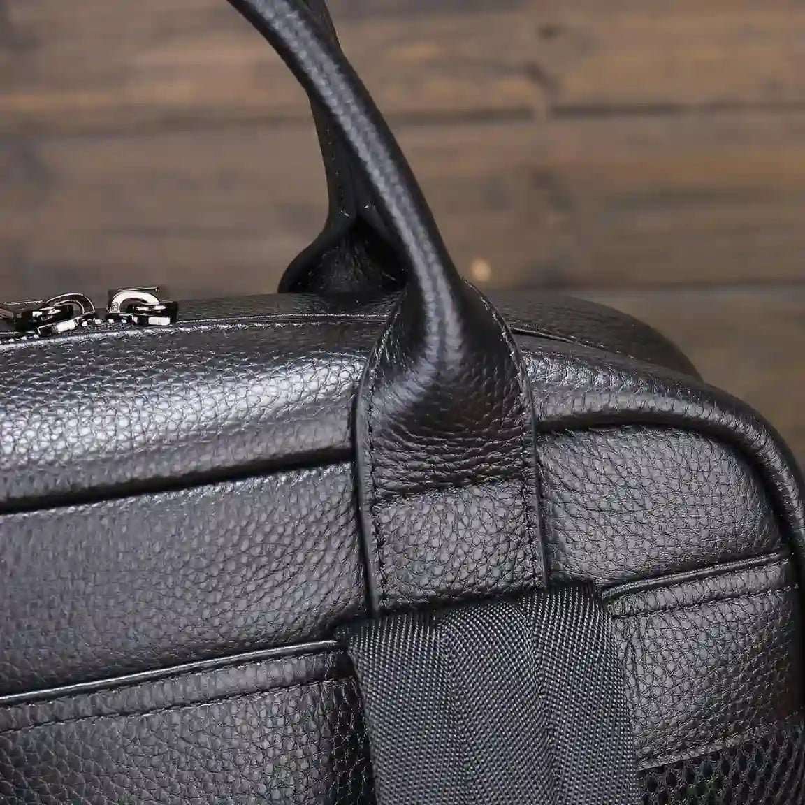 Close-up view of a black leather bag showcasing its textured surface and sturdy handles.