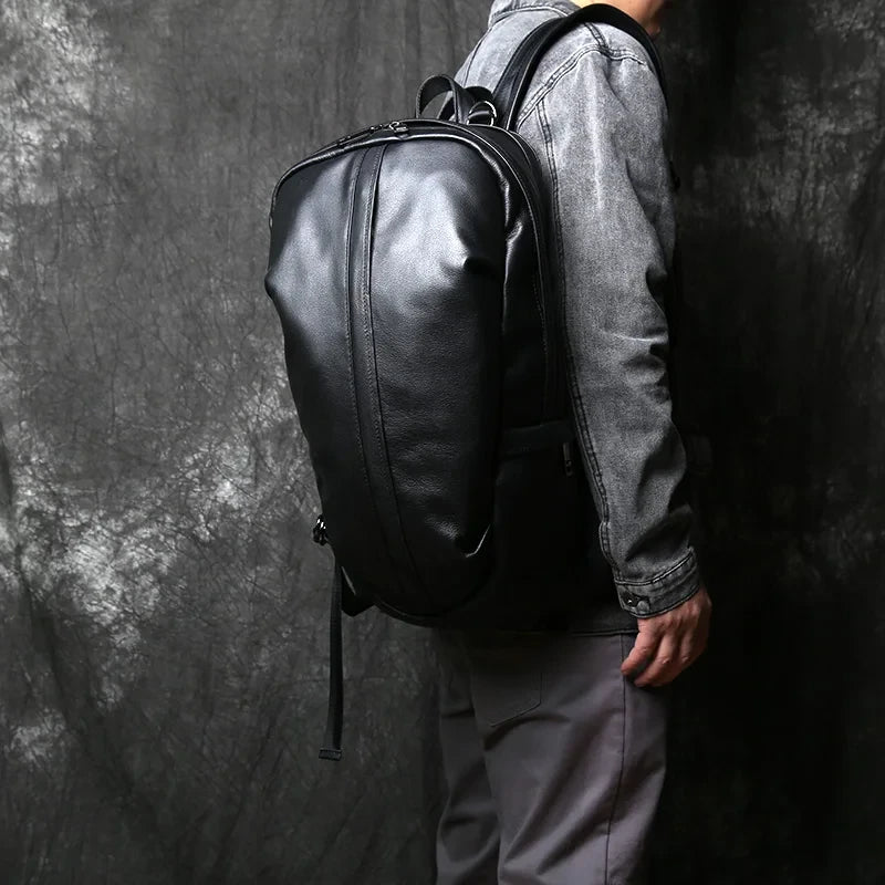 A man wearing a black leather backpack on shoulder, highlighting the modern and minimalist style of the backpack.