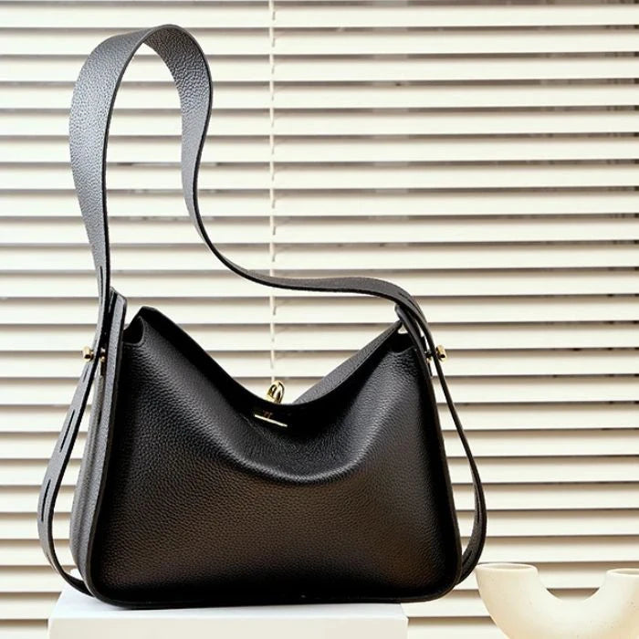 Black leather bag with adjustable strap and modern, elegant design, front view.