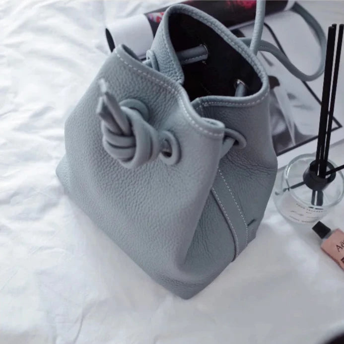 An elegant light blue handbag featuring a unique knot closure, ideal for everyday use.