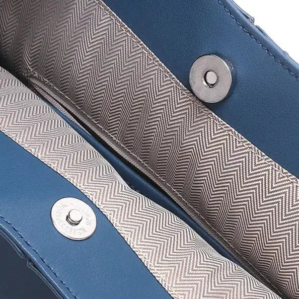 Detail of a blue bag with a zigzag pattern on the inside, and magnetic button for cloure.