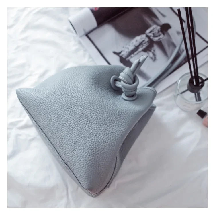 Stylish blue leather handbag with unique knot detail.