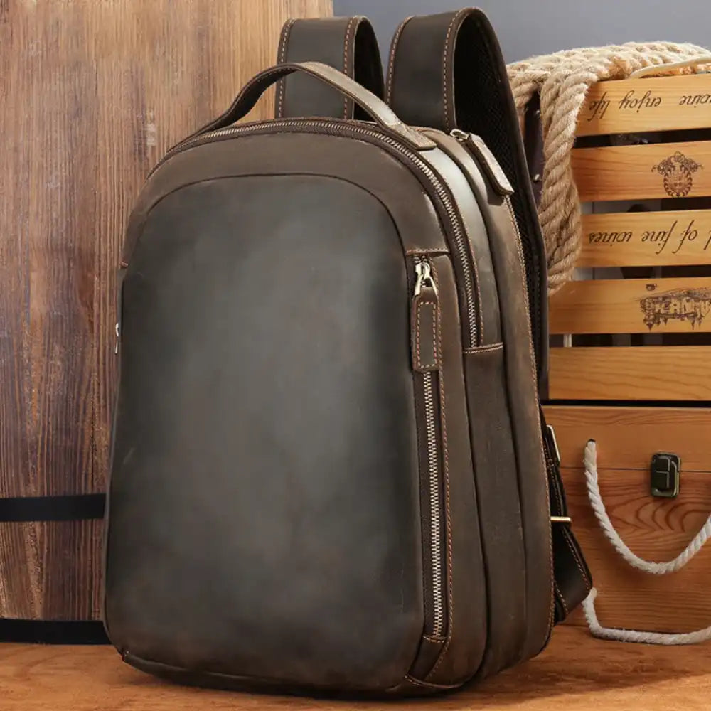Vintage-inspired brown leather backpack with adjustable straps, soft handle and multiple compartments, front view.