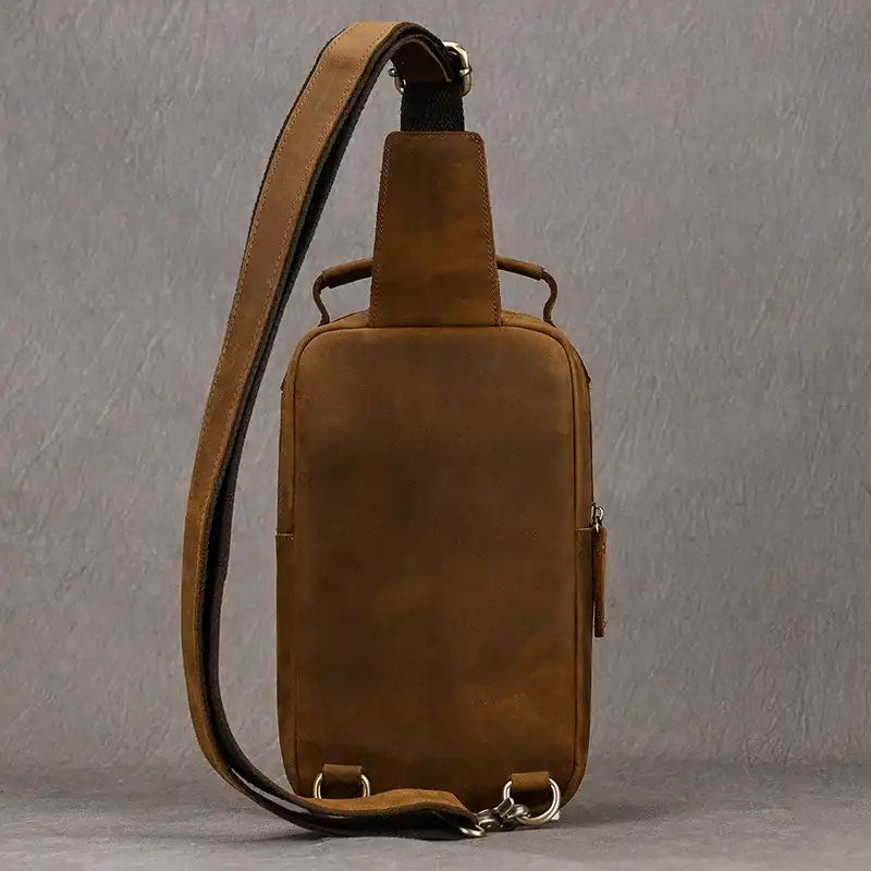 Brown leather crossbody bag with soft handle and adjustable strap, back view.
