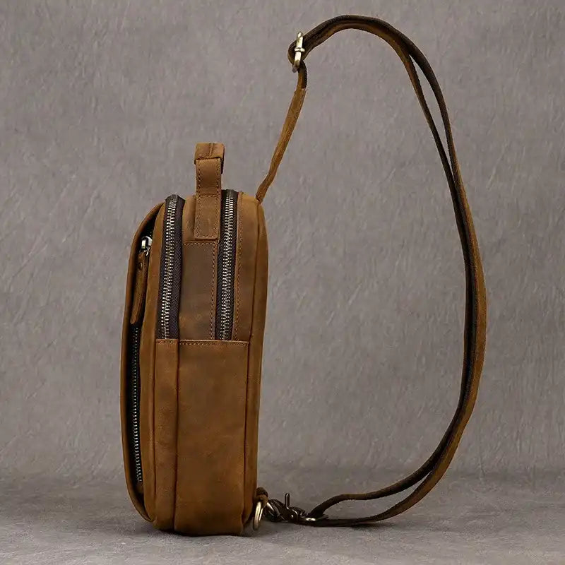 Brown leather crossbody bag with soft handle and adjustable strap, side view.