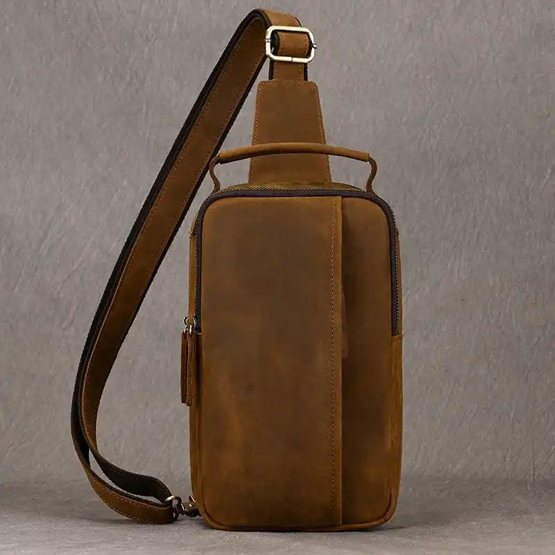 Brown leather crossbody bag with front pocket and adjustable strap, front view.
