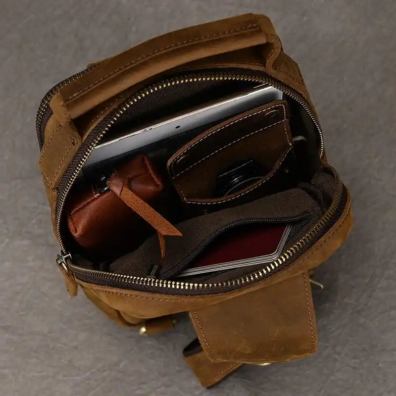 open brown leather backpack showing its interior, with several compartments and organized items inside.