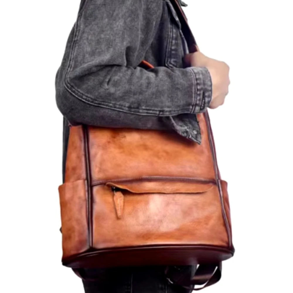 Brown leather bag with front pocket and zipper detail worn on shoulder.