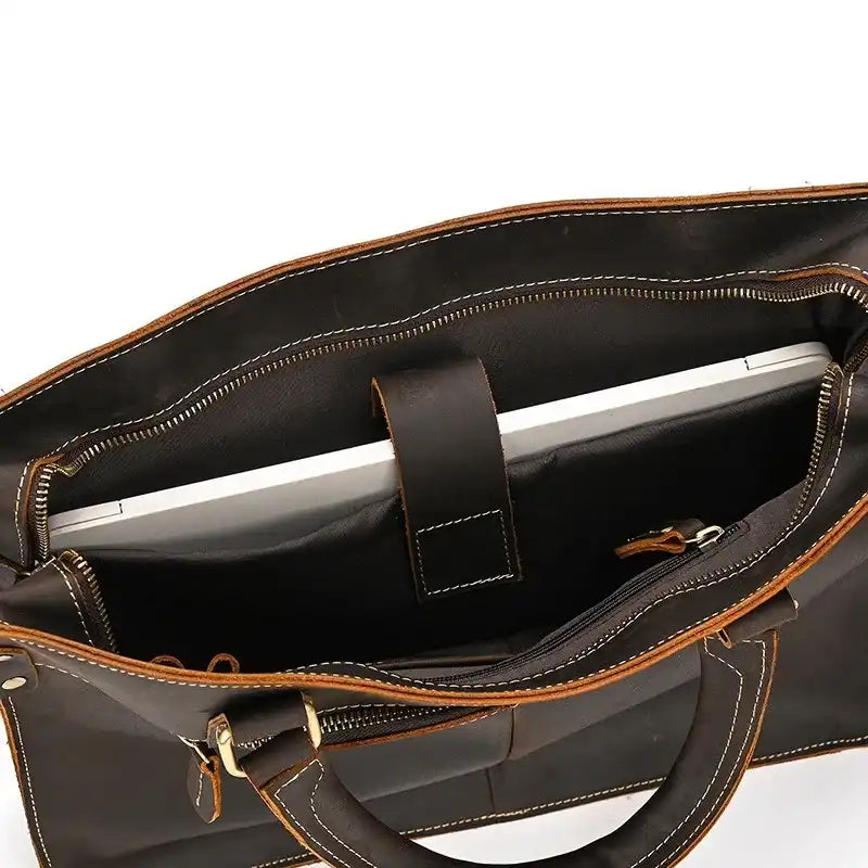 interior view of a brown leather bag with a laptop held in place. The bag has light stitching and is ideal for work.