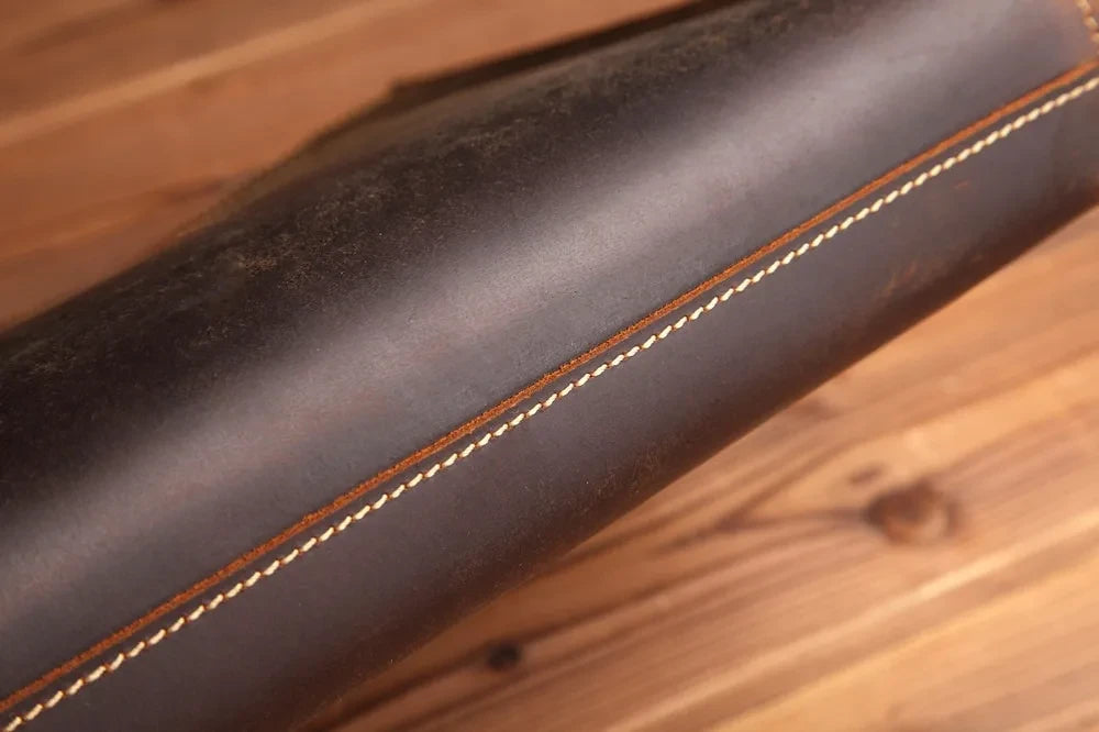A dark leather material with light stitching, highlighting its rich texture and sophisticated finishes.