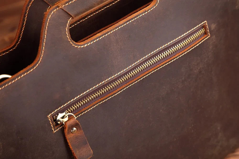 Detail of a brown leather bag with a zipper, highlighting the stitching and texture of the material. 