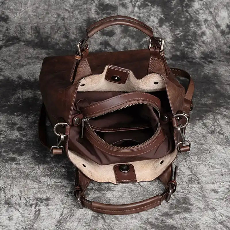 Interior of a brown leather handbag with compartments, showing zipper pockets, compartments and fine details.