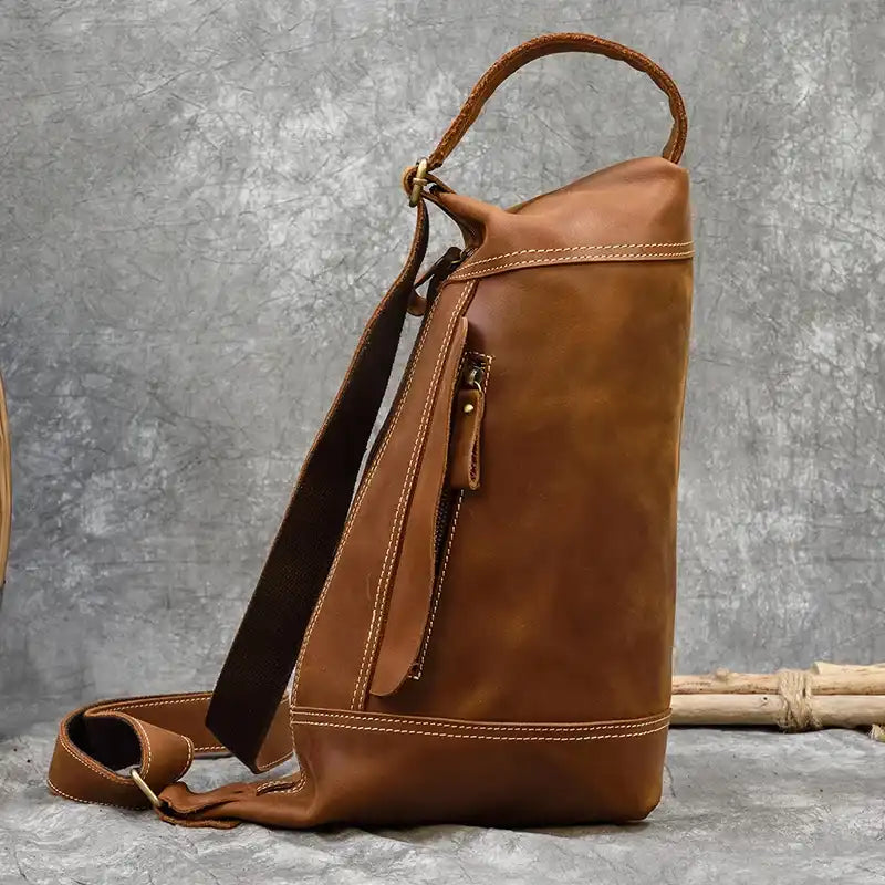 Side view of a light brown leather bag with zipper pocket showcasing its craftsmanship and unique design.