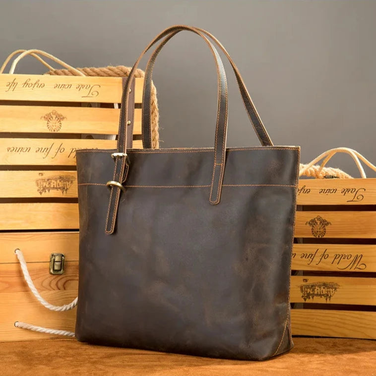 Stylish dark brown leather tote bag against a wooden background.