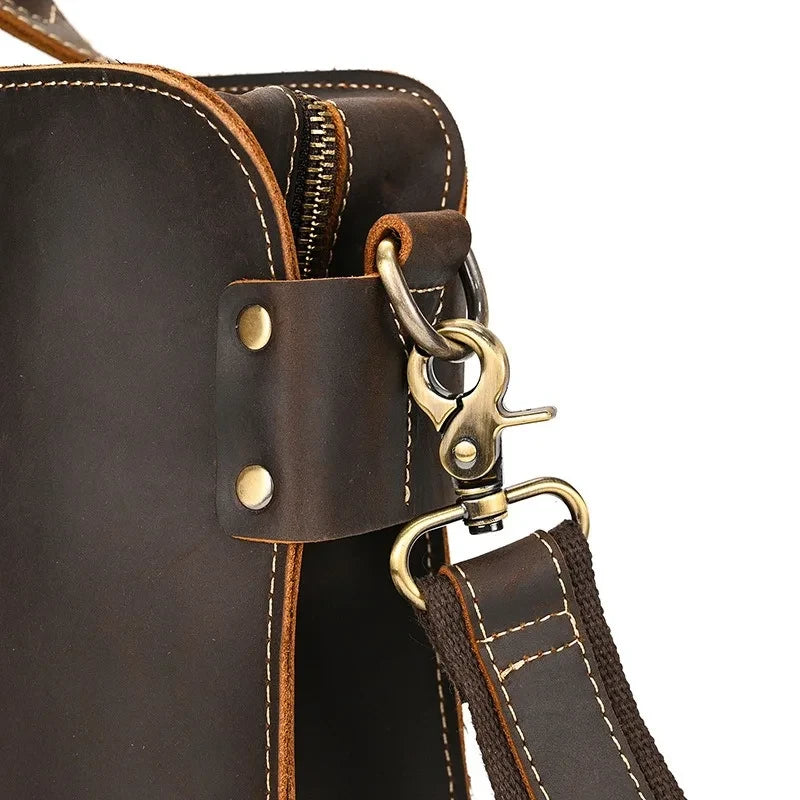 Detail of a coffee brown leather suitcase with zipper closure and detachable strap.