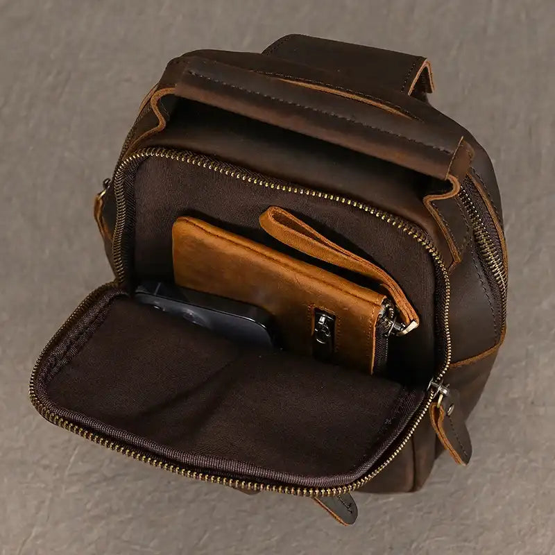 brown leather crossbody with dark leather accents, showing the interior compartments and organized items.