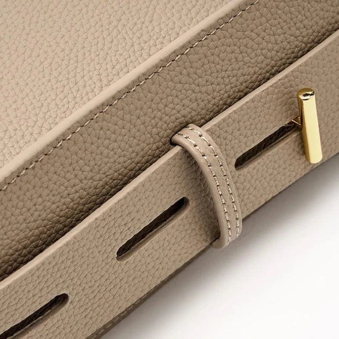 Detail of an elegant leather bag djustable strap, highlighting the textured leather finish and the gold clasp.