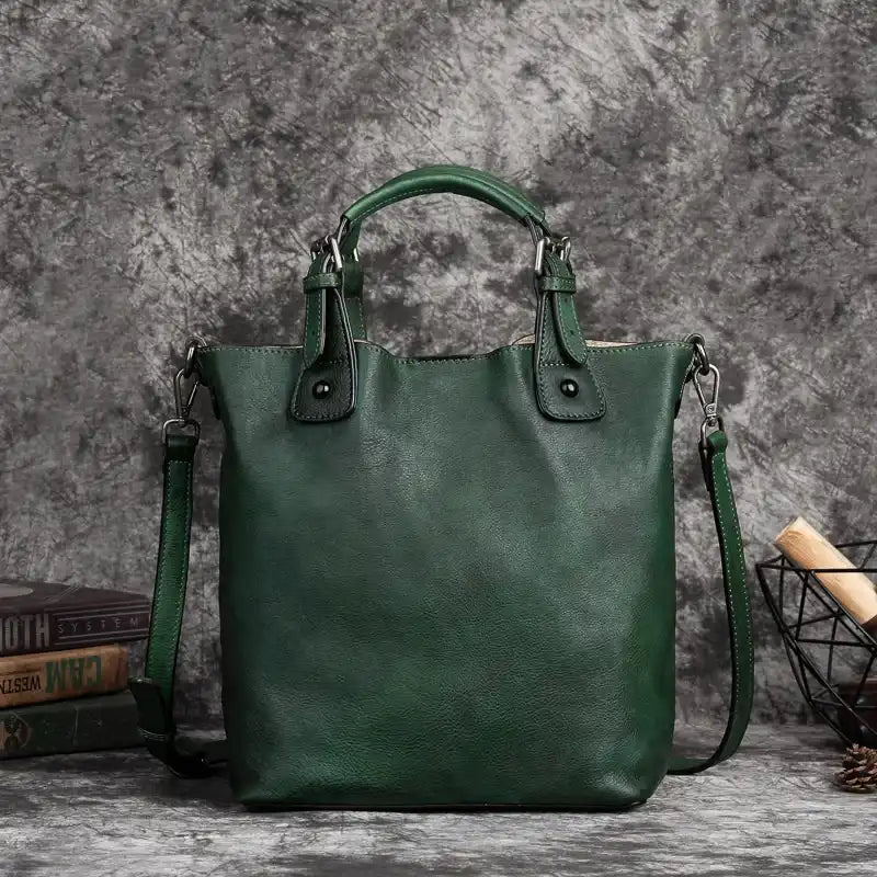 green leather handbag with handles, adjustable strap and metal details, front view.