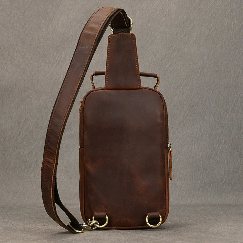 Red brown leather crossbody bag with soft handle and adjustable strap, back view.