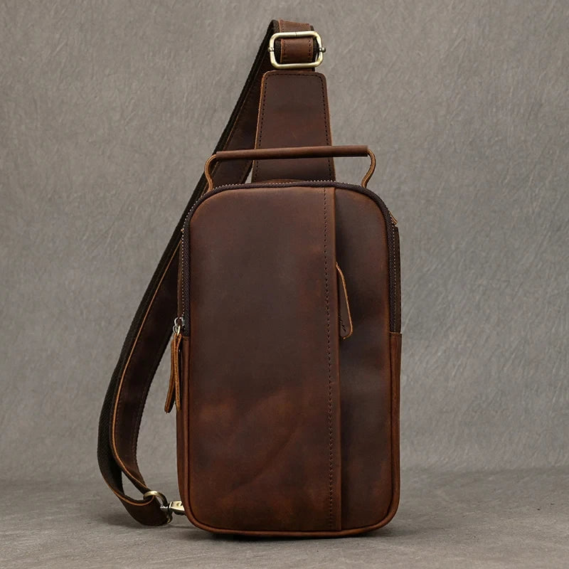 Red brown leather crossbody bag with front pocket and adjustable strap, front view.