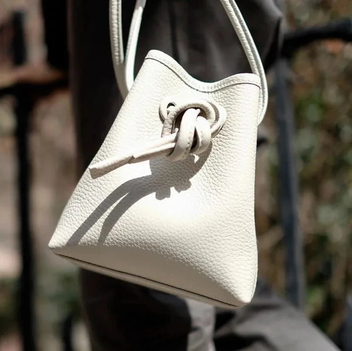close-up on a stylish white leather bag with a unique knot design.
