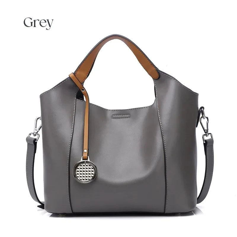 Grey leather bag with soft detachable handles and elegant charm, front view.
