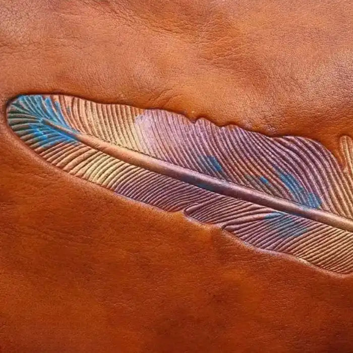 Image of a stylized leaf embossed in brown leather, with colored details that highlight its texture and shape. 