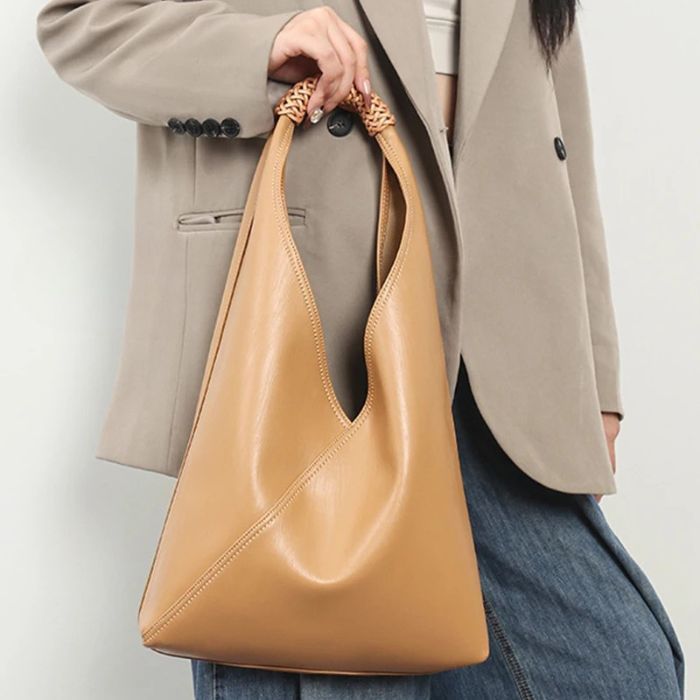 A woman holding a gold-colored leather bag, combined with a beige blazer.