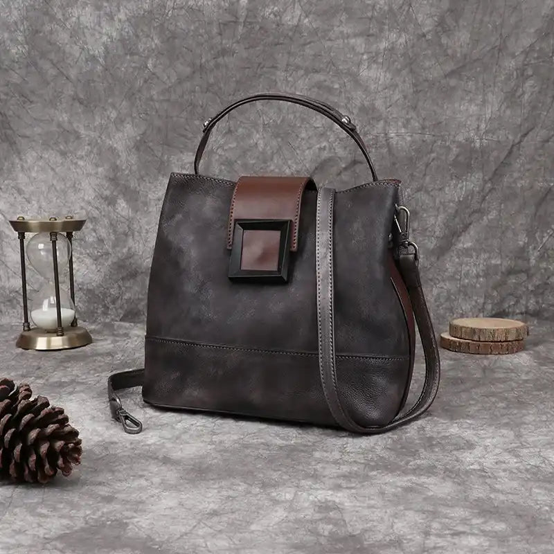 Gray women leather handbag with brown details, soft handle and adjustable strap, front view.