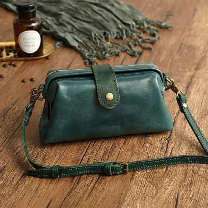 Green leather shoulder bag with leather adjustable strap and snap closure, front view.
