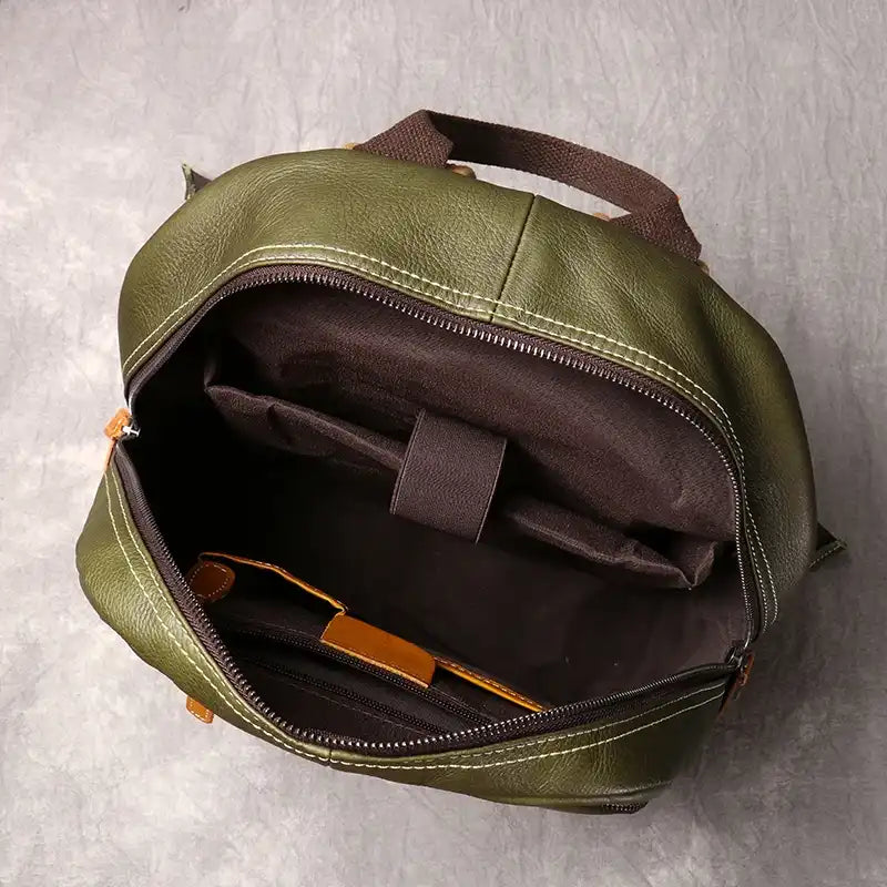 Inside view of a green leather backpack, showing compartments and brown lining and interior pockets.