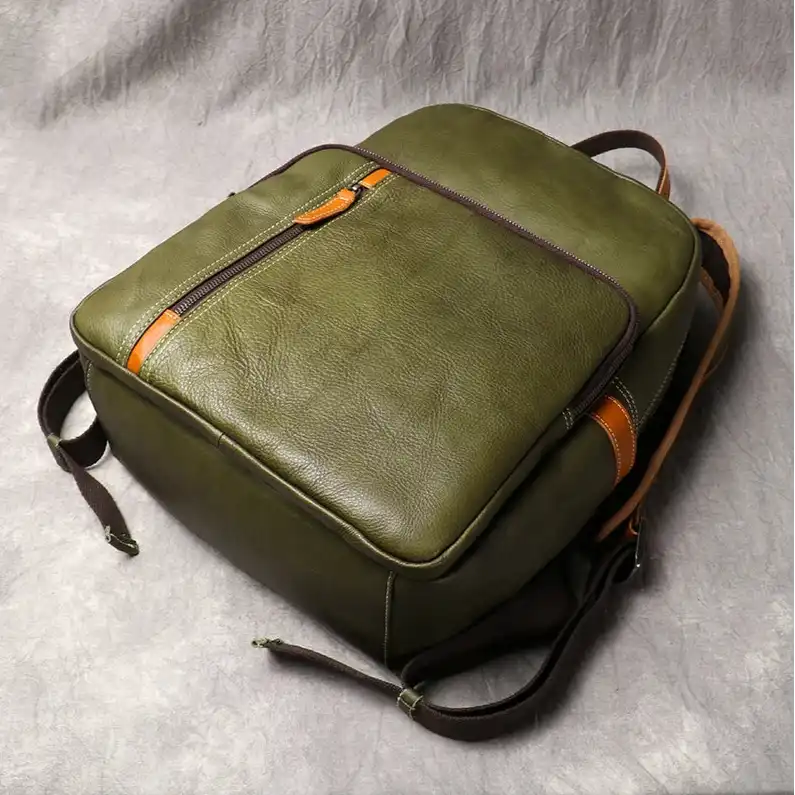 Green leather backpack with orange details, ideal for daily use and travel. Practical and modern design, top view.