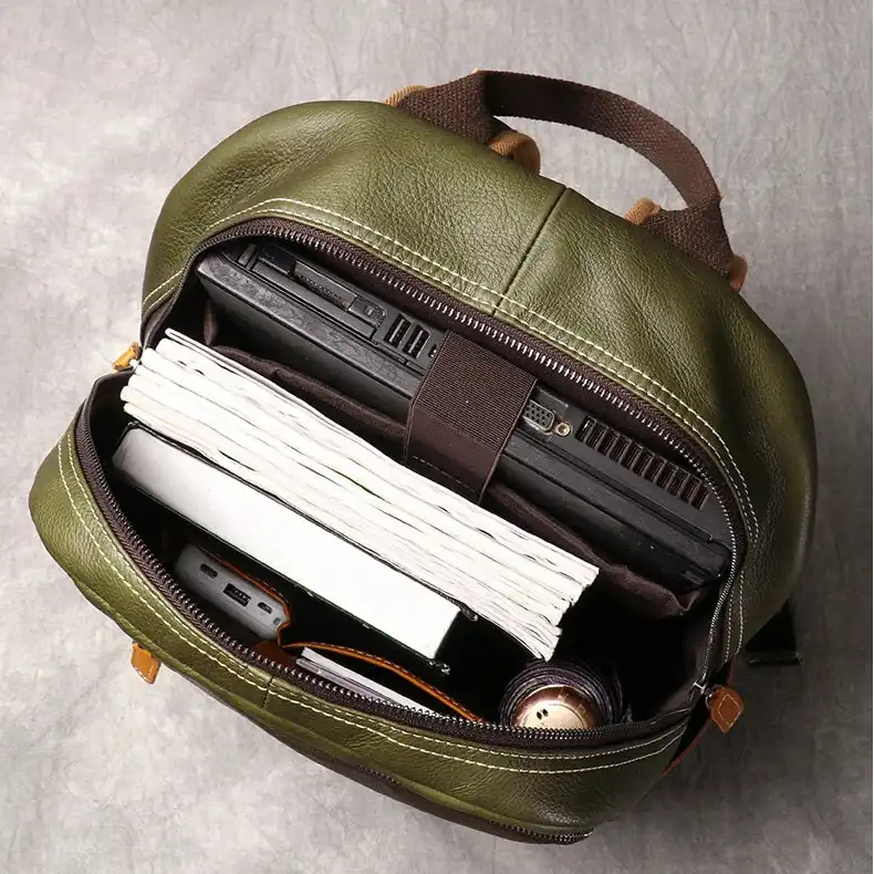 Top view of a green leather backpack, displaying laptop, notebooks and other items organized, ideal for students and professionals.