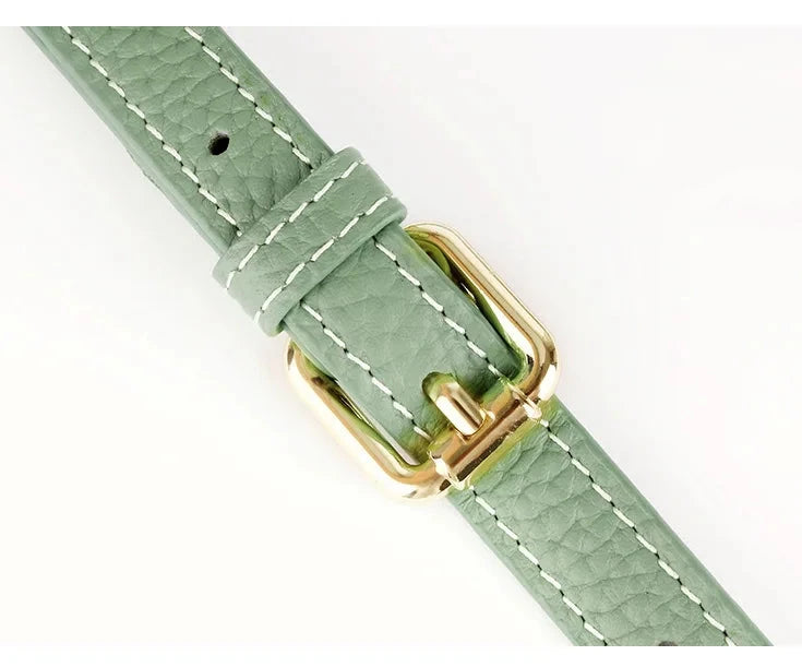Close up on High-quality green leather bag strap with a shiny gold buckle.