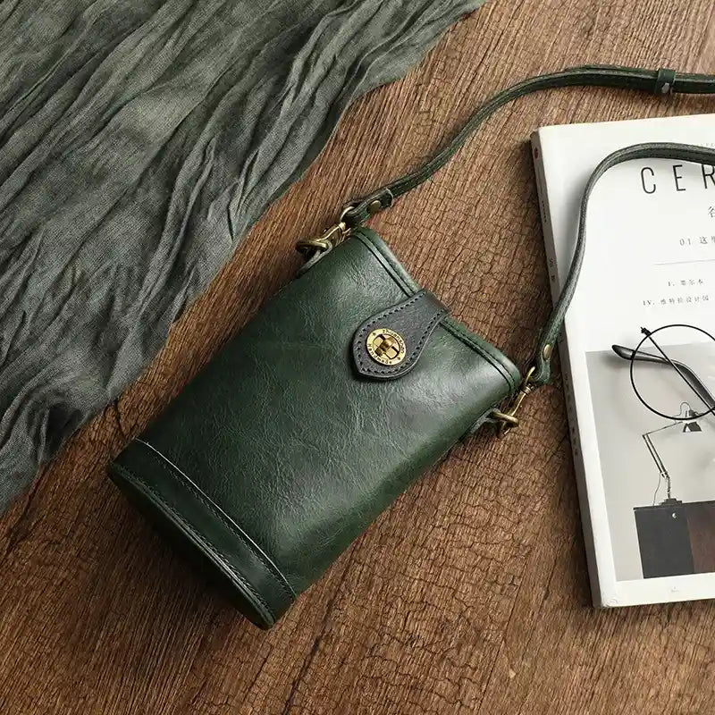 Chic green leather crossbody bag with gold accents on a rustic background.