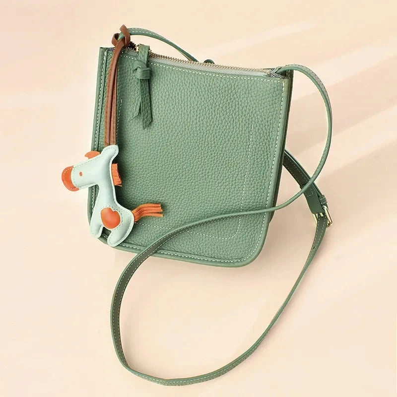 Trendy green crossbody bag featuring a playful horse charm - front view