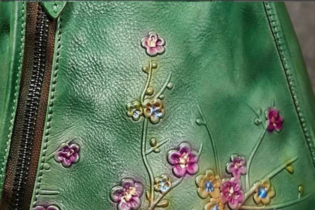 Close-up of a floral embossed design on a green leather bag.