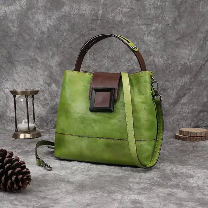 Green women leather handbag with brown details, soft handle and adjustable strap, front view.
