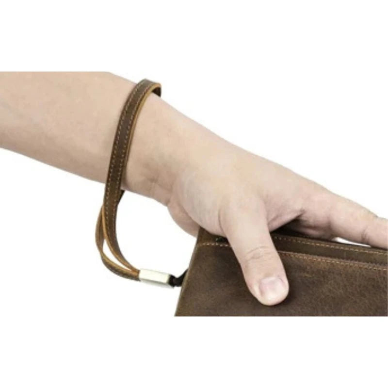 A hand holding a brown leather clutch with a wrist strap, ideal for everyday use and special occasions.