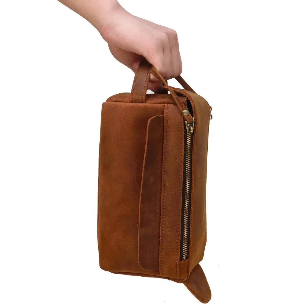Side view of a brown stylish leather clutch being held by a hand.