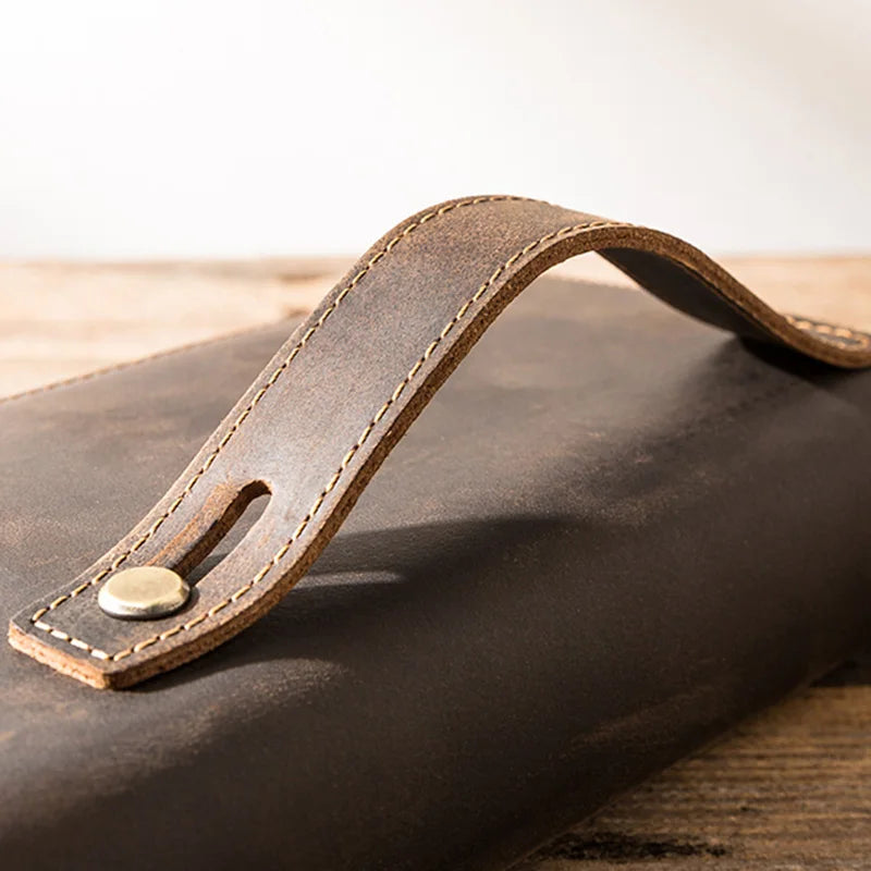 Close-up of a brown leather wallet wrist strap showcasing its stitching and brass button.