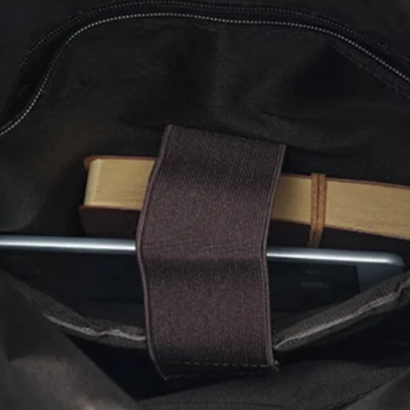 Inside view of a bag showing a mobile device and a notebook in internal pocket.